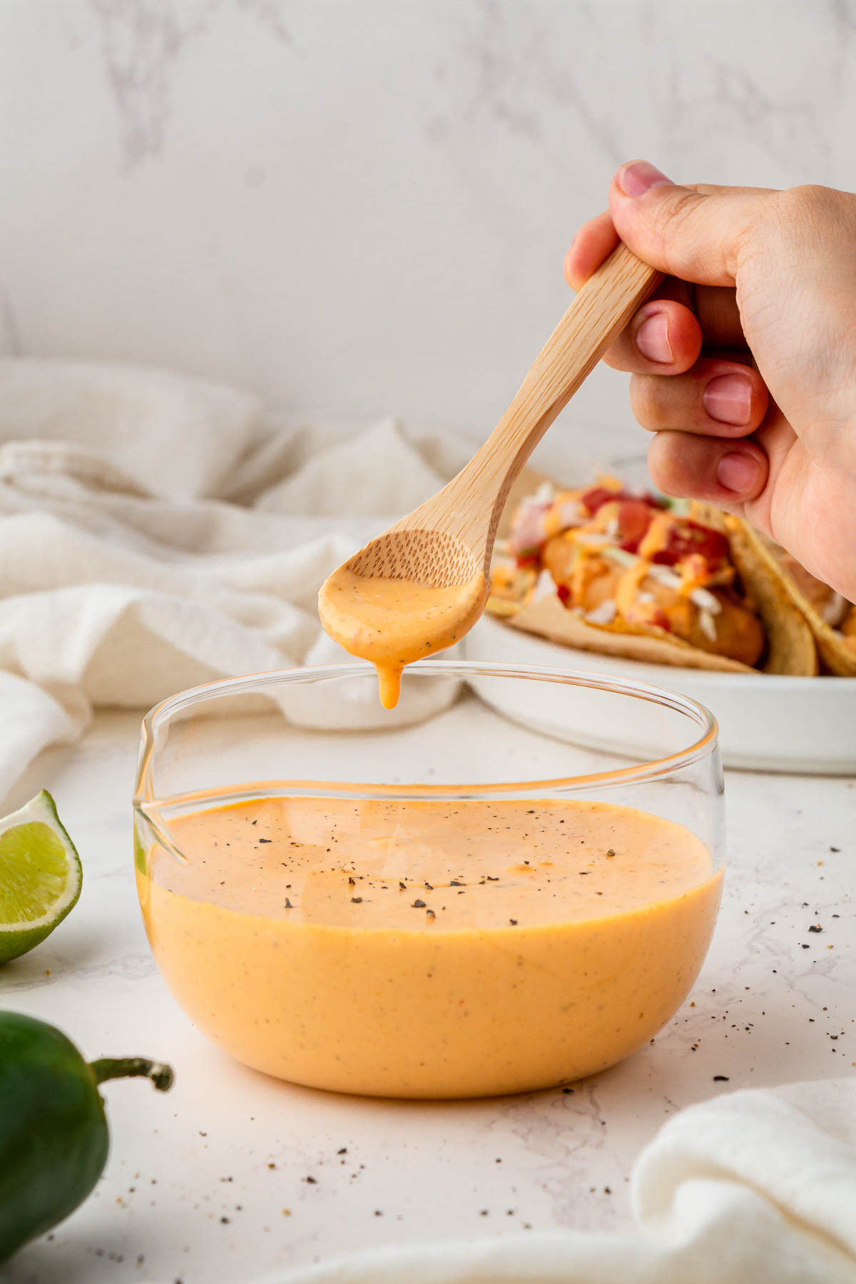 overhead view of baja sauce in glass serving bowl with wooden spoon scooping sauce