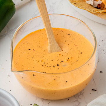 overhead view of baja sauce in glass serving bowl with wooden spoon