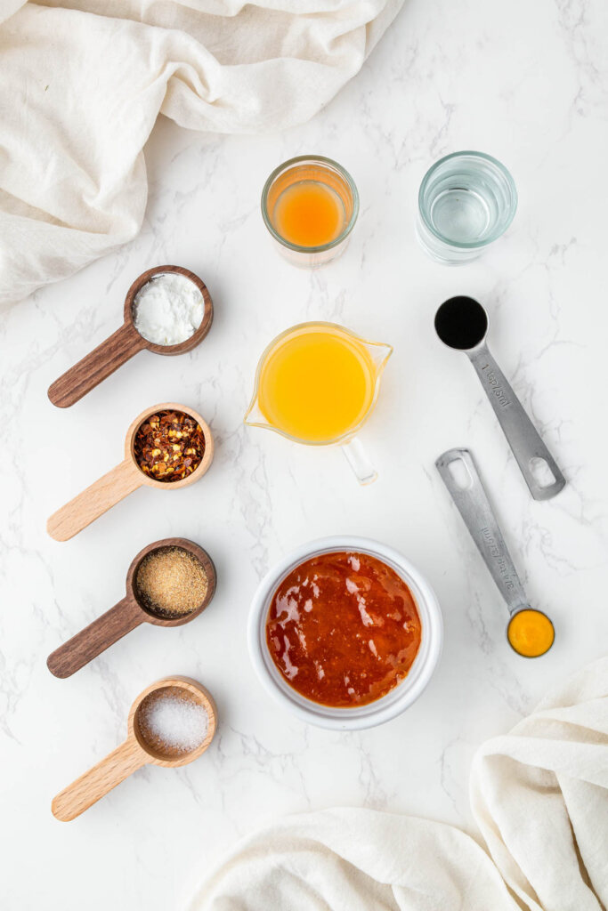 overhead view of individual ingredients for McDonalds sweet and sour sauce in individual bowls and spoons on white surface