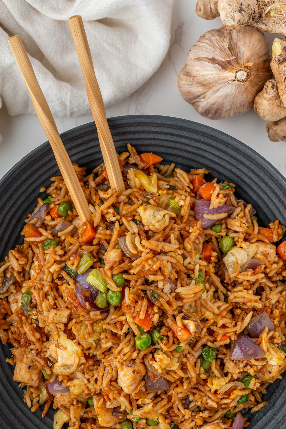 close up of PF Changs chicken fried rice in black bowl with wooden chopsticks