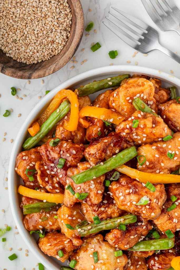 close up of white bowl of Panda Express Sesame Chicken with peppers and green beans