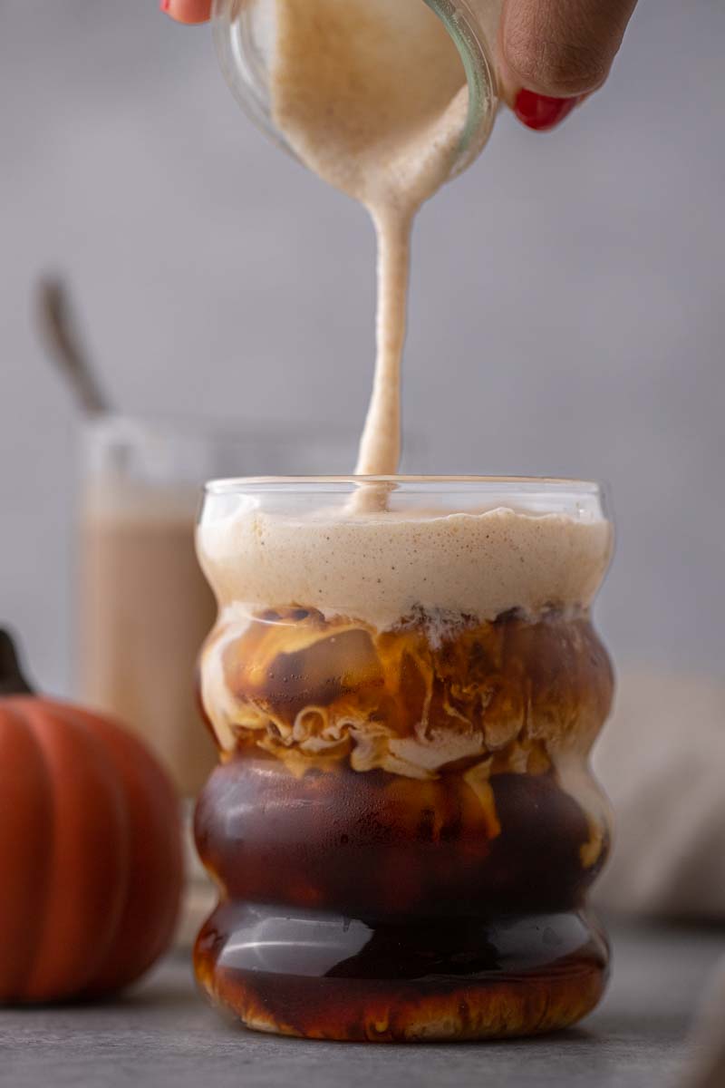 Starbucks pumpkin cold foam being poured into a cup of coffee