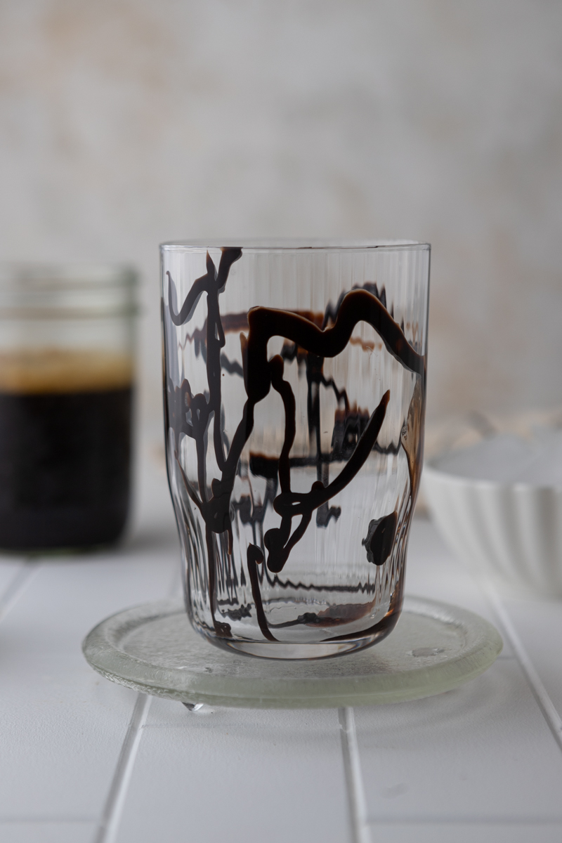 tall empty glass with chocolate syrup drizzled on the inside of the walls