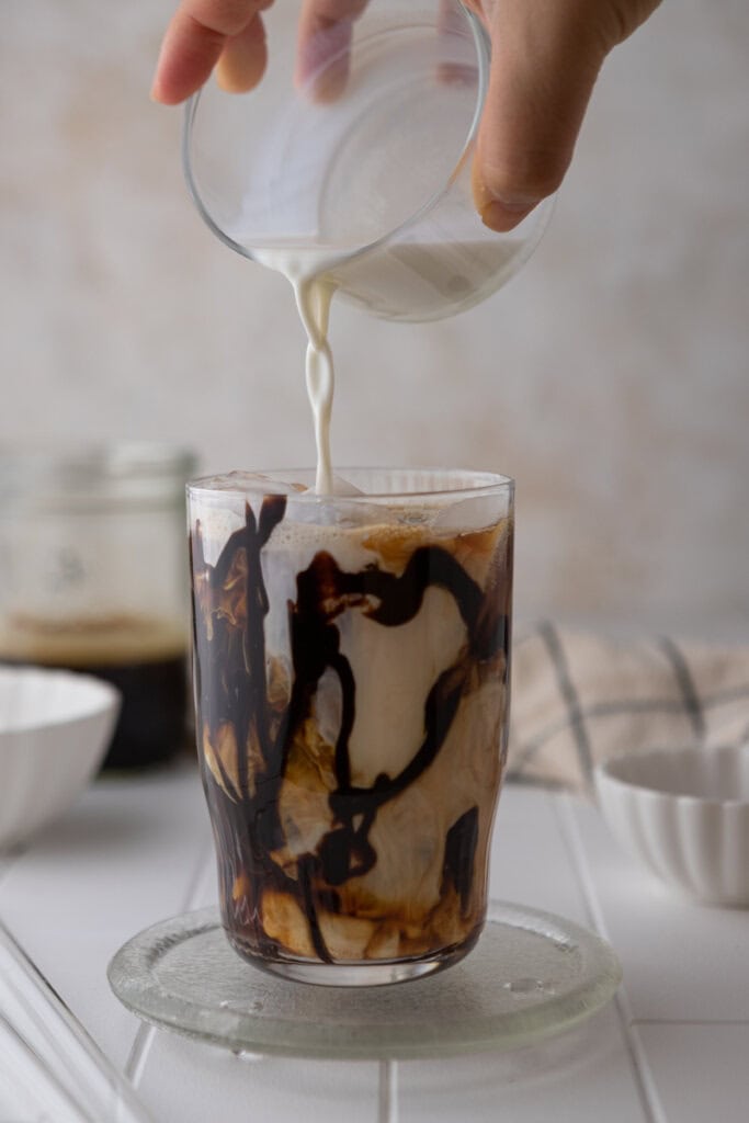 Pouring homemade sweet cream into iced mocha coffee