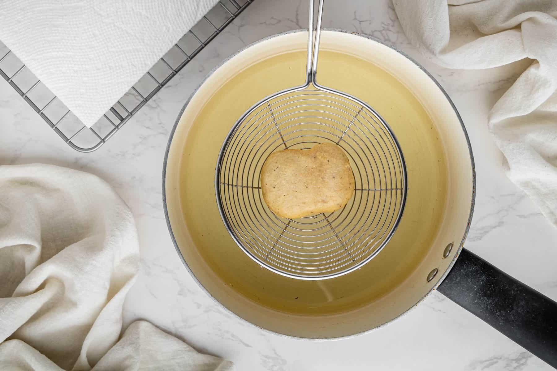 chicken nugget getting lowered into hot oil to cook