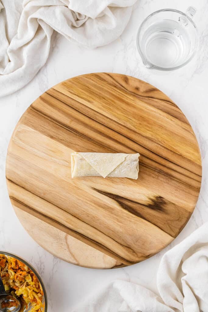 overhead view of Panda Express Chicken Egg Roll wrapped up on wooden platter