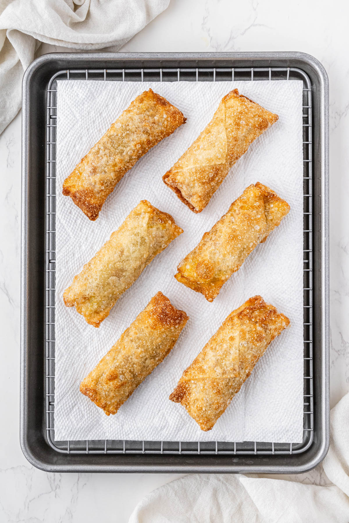 cooked panda express chicken egg rolls laying on parchment paper covered baking sheet