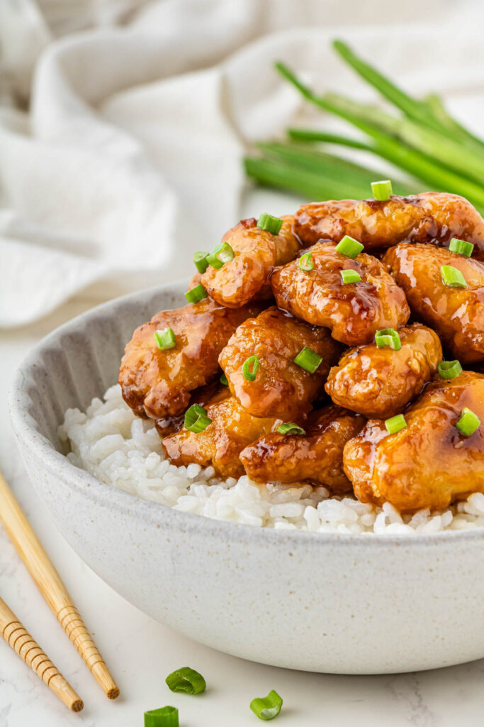 Orange Chicken on top of a bed of rice in a grey bowl