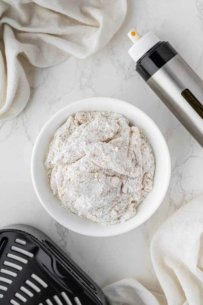 chicken pieces covered in flour breading in white bowl