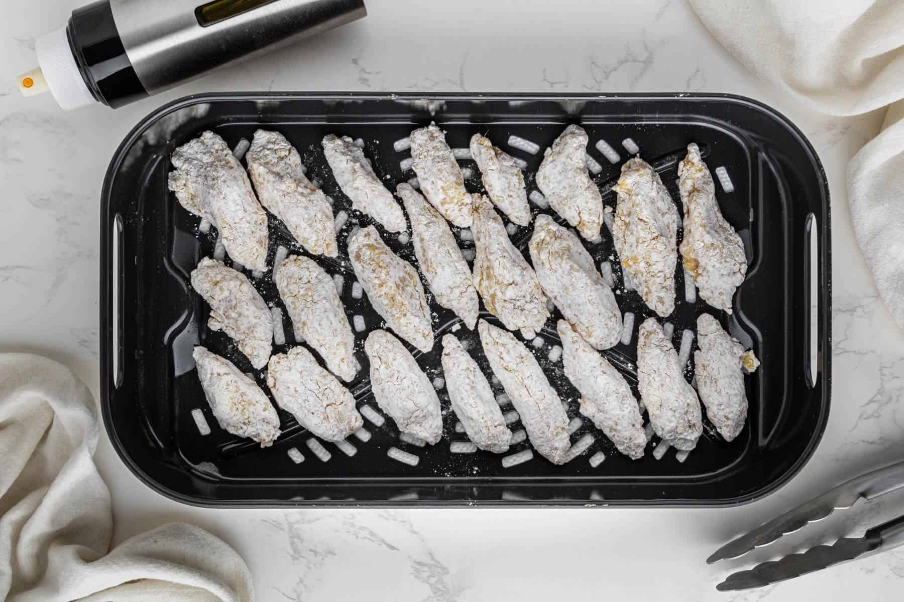 overhead view chicken pieces covered in flour breading in air fryer basket