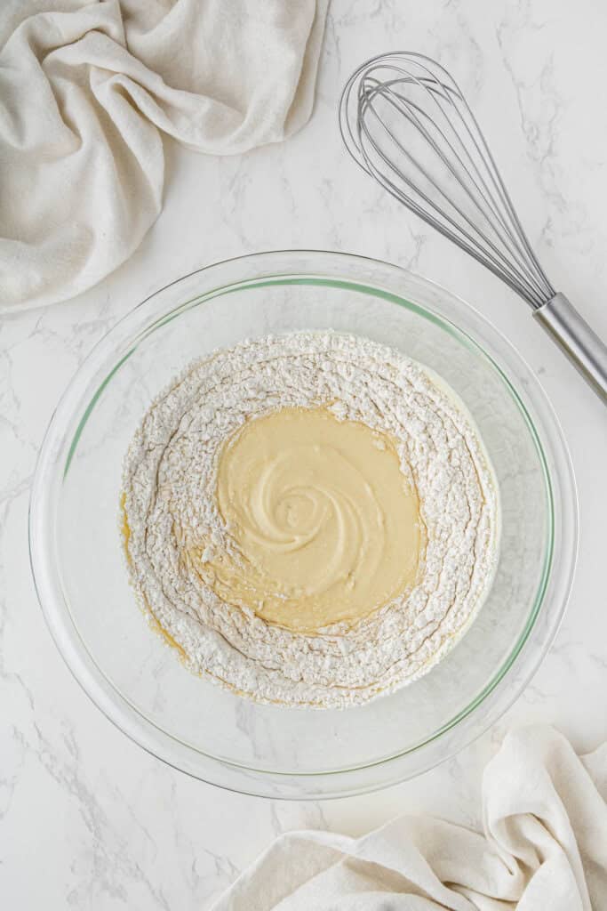 adding wet ingredients to dry ingredients bowl