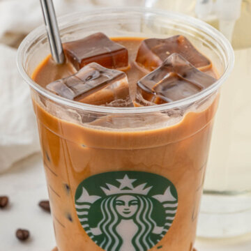 Starbucks Iced Shaken Espresso with milk with metal straw on wood coaster