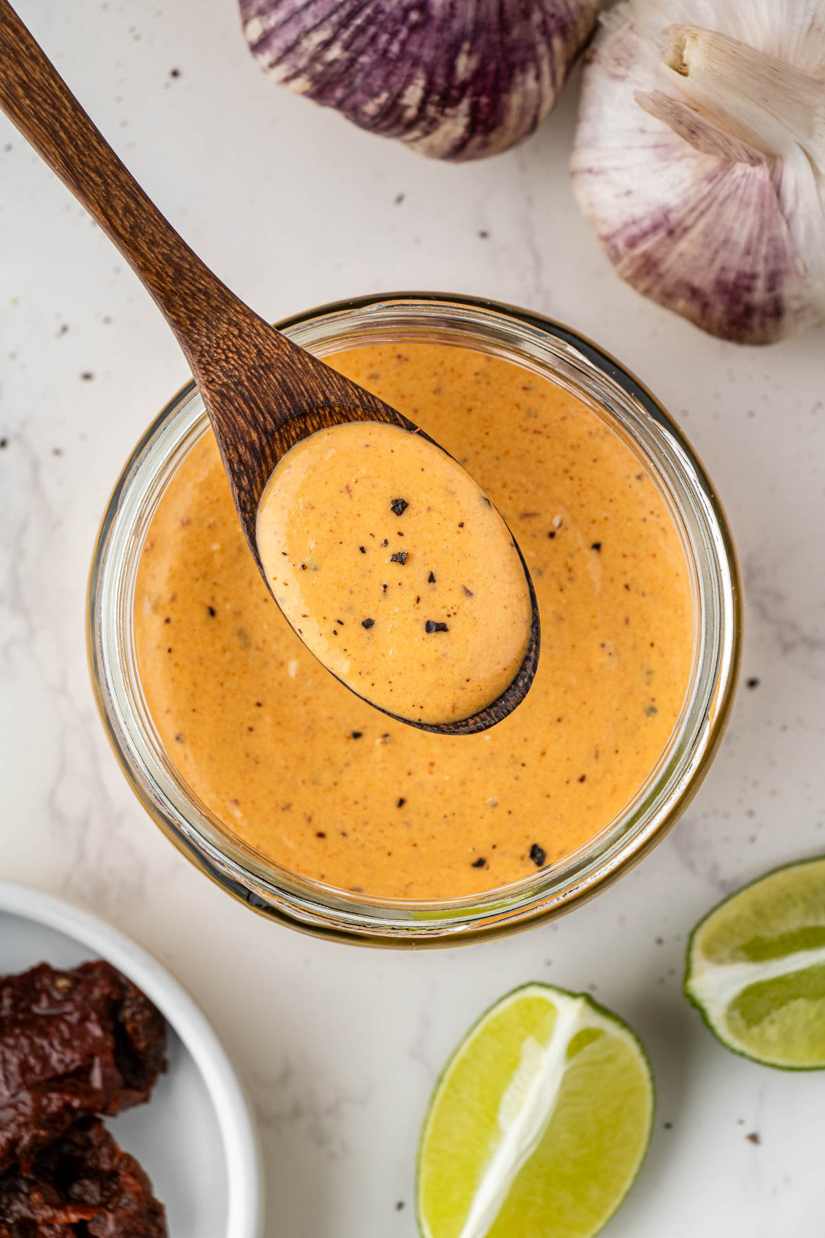 overhead view of chipotle sauce with wooden spoon holding over glass jar