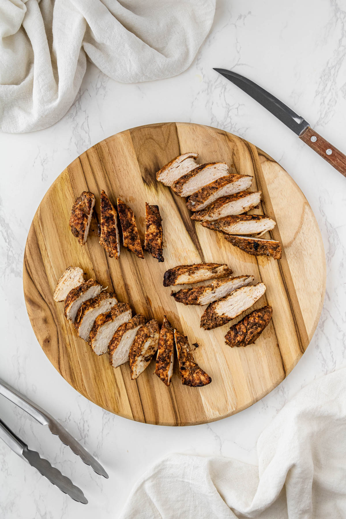 cut chipotle chicken breasts on wooden circle platter with knifed on the side