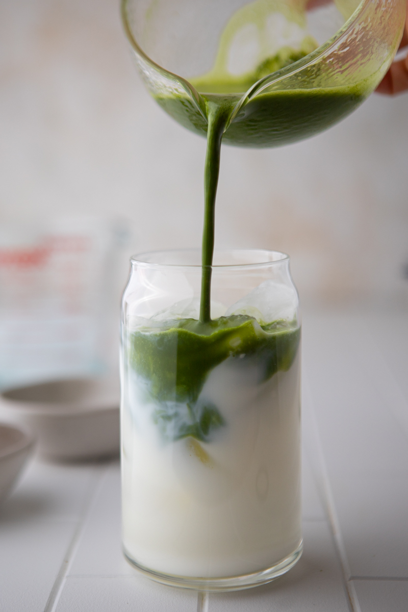 matcha being poured into the glass over the milk