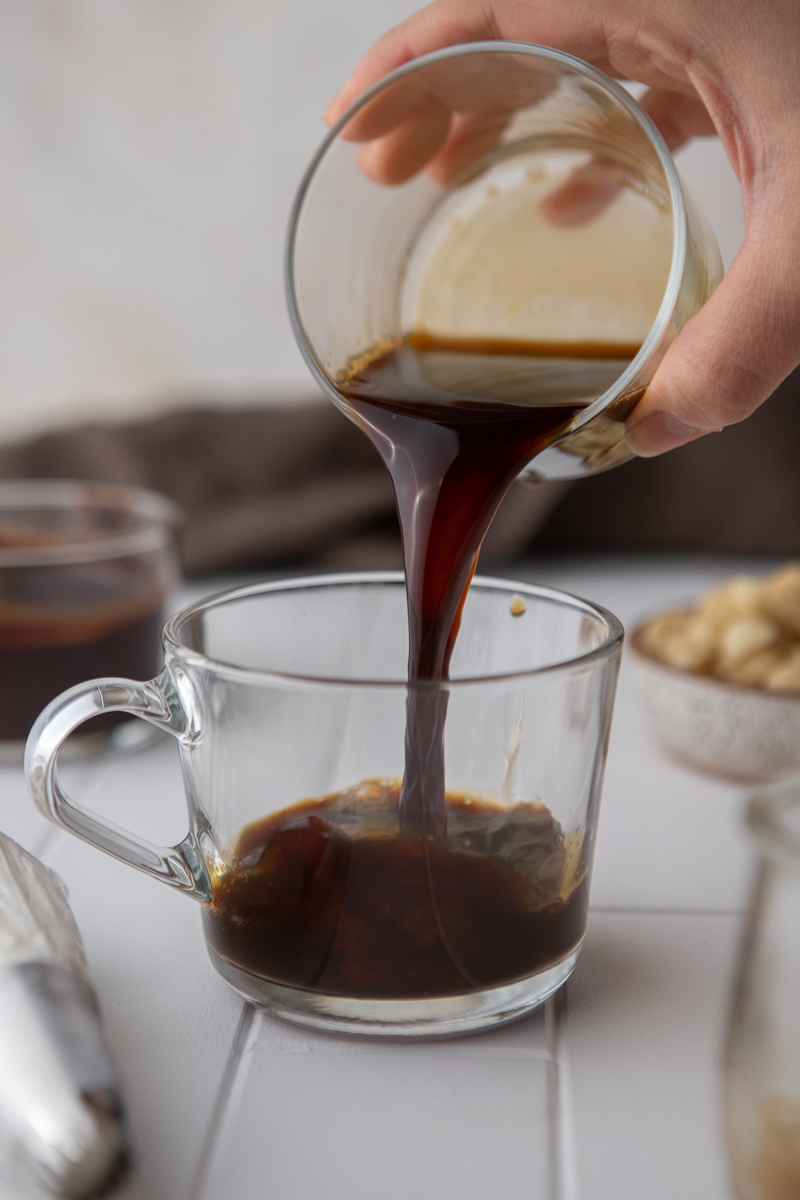 espresso being poured into a cup over the syrup