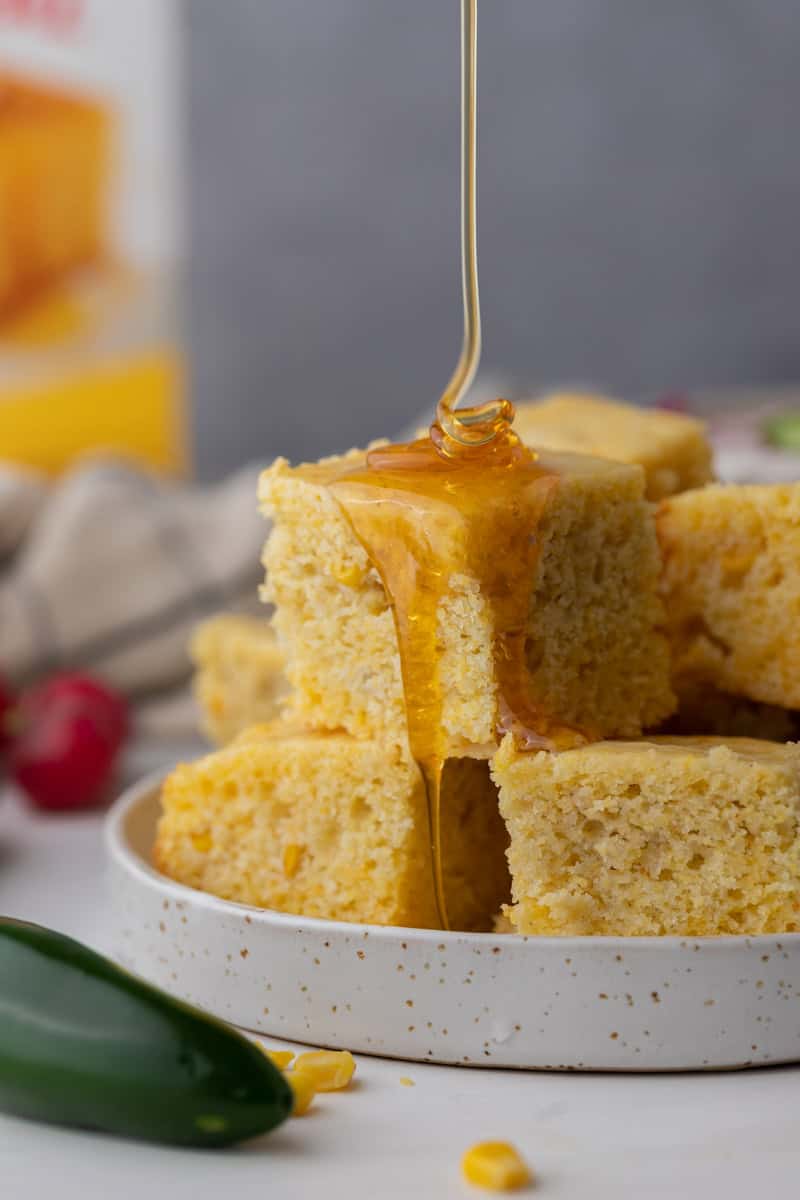 individual squares of krusteaz cornbread getting honey drizzled on it