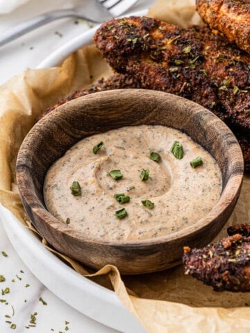 side view of wooden cup of Popeyes Blackened Ranch in basket with blackened chicken tenders