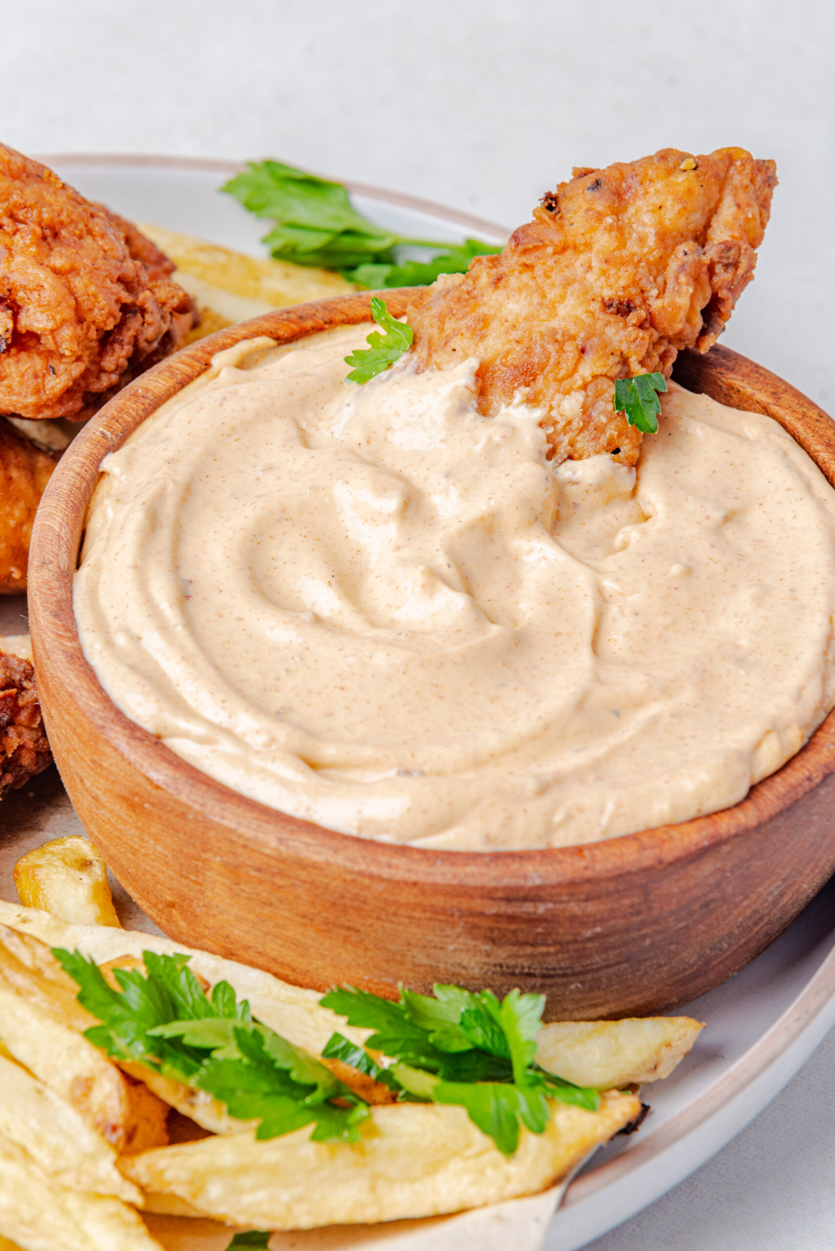 a chicken tender dunked in a cup of Popeyes spicy mayo recipe