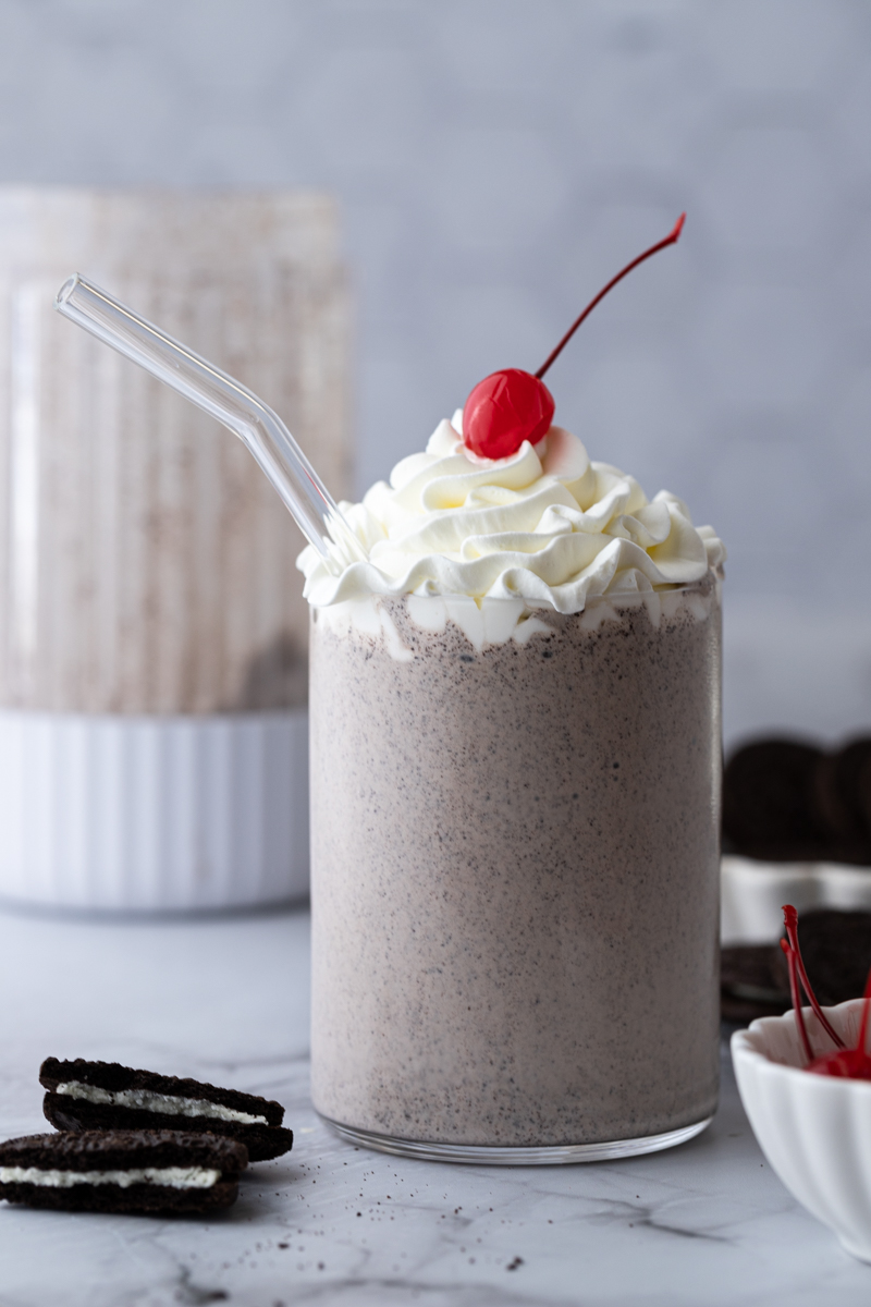 The Chick-fil-A cookies and cream milkshake in a glass with whipped cream and cherry on top