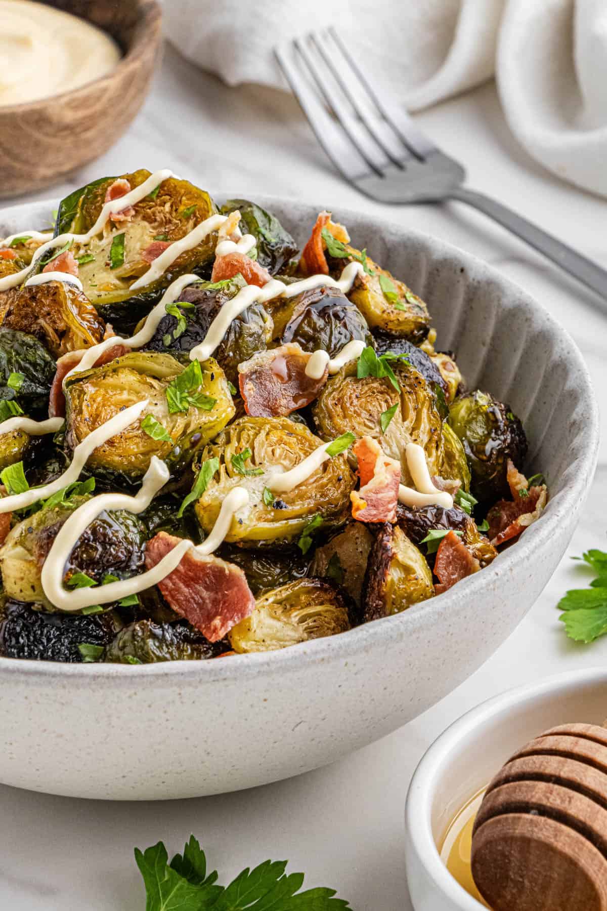 bowl of outback brussels sprouts with bacon bits and lemon aioli drizzled on top