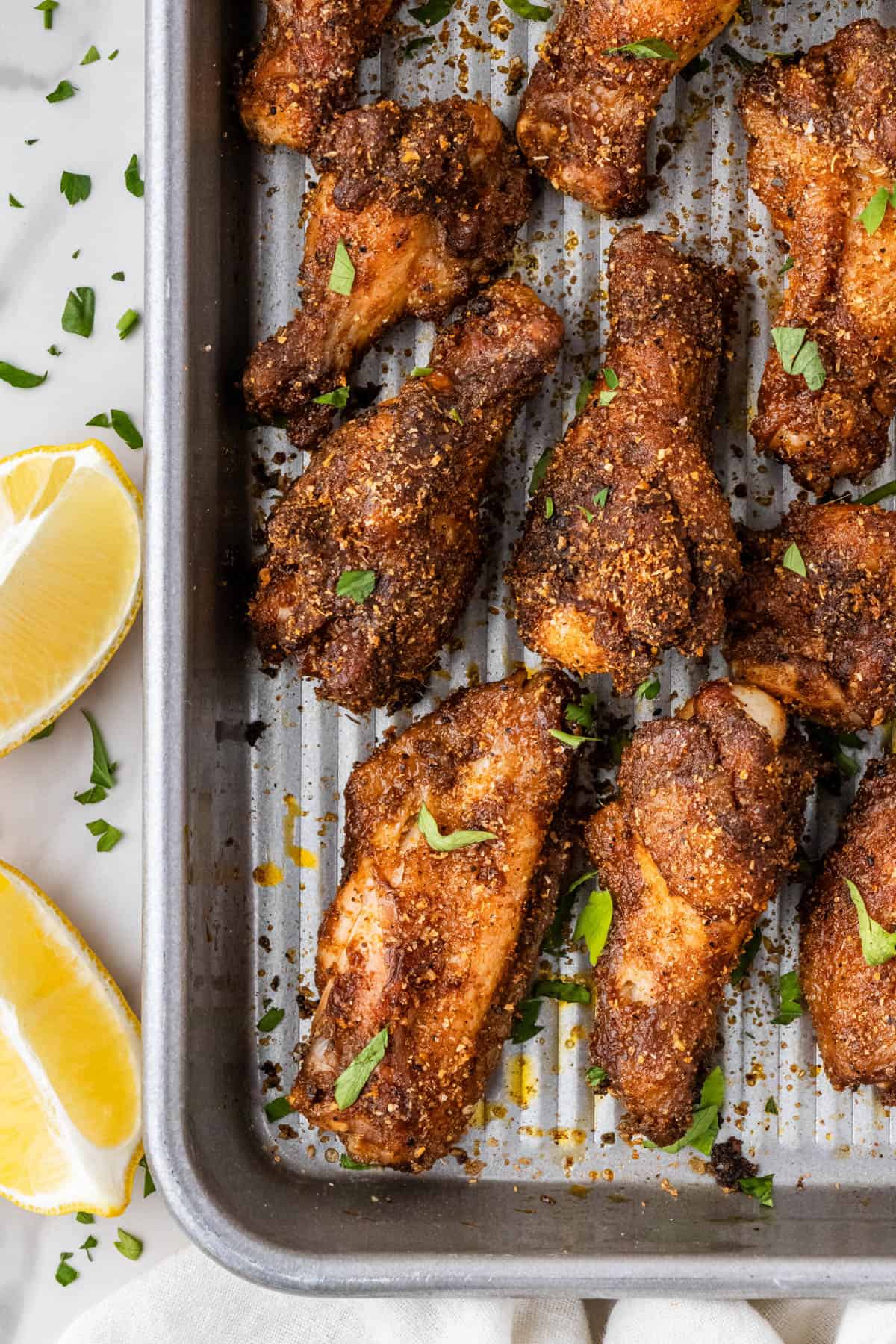 close up of chicken on baking sheet with lemon in background