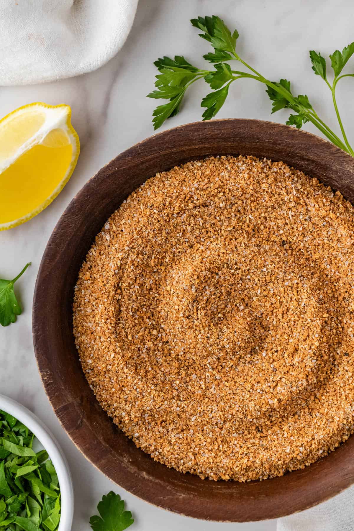 copycat Buffalo Wild Wings dry rub recipe in brown bowl with lemon and fresh herbs in the background