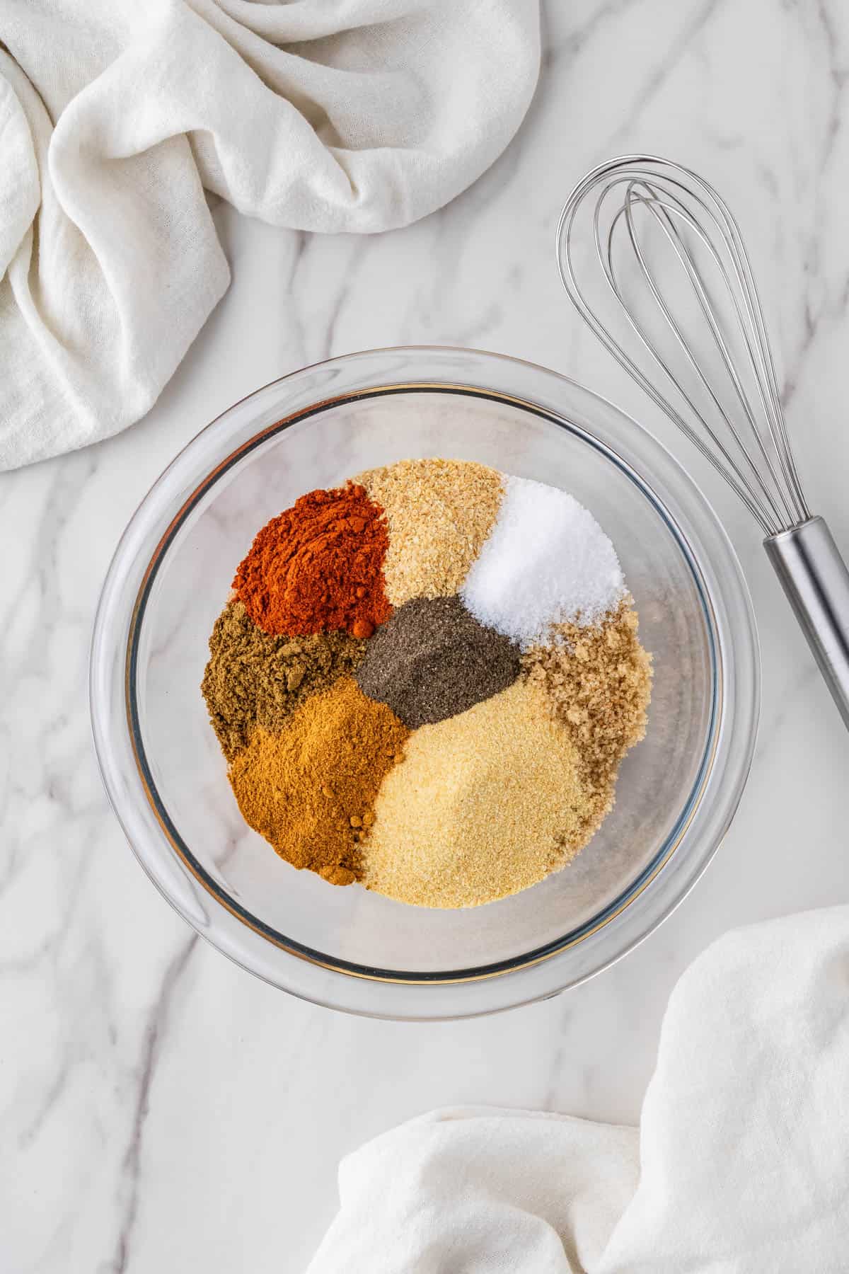 overhead view of the ingredients in clear bowl with whisk on the side