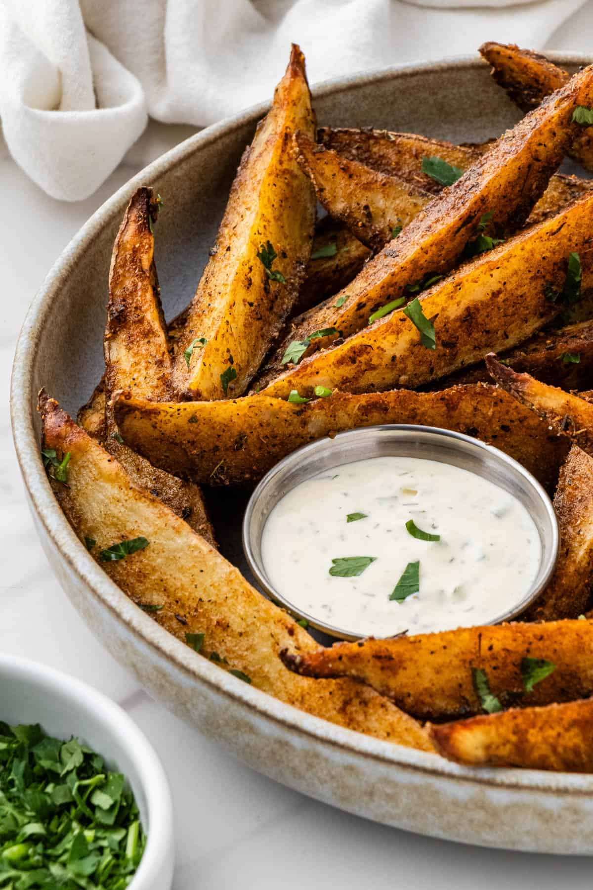 cup of ranch surrounded by seasoned copycat buffalo wild wings potato wedges