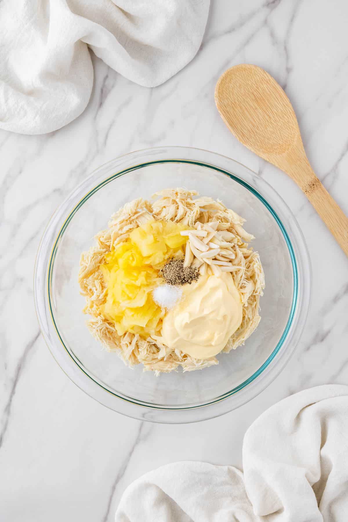 ingredients in clear bowl with wooden spoon next to it