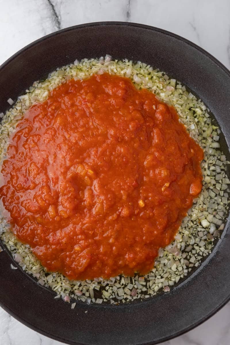 tomato sauce poured over the garlic and onion in the pan