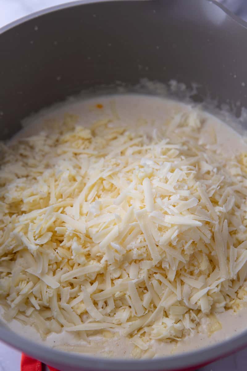 shredded cheese being added to the pot