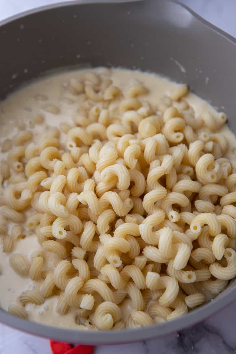 pasta being added to the pot of sauce