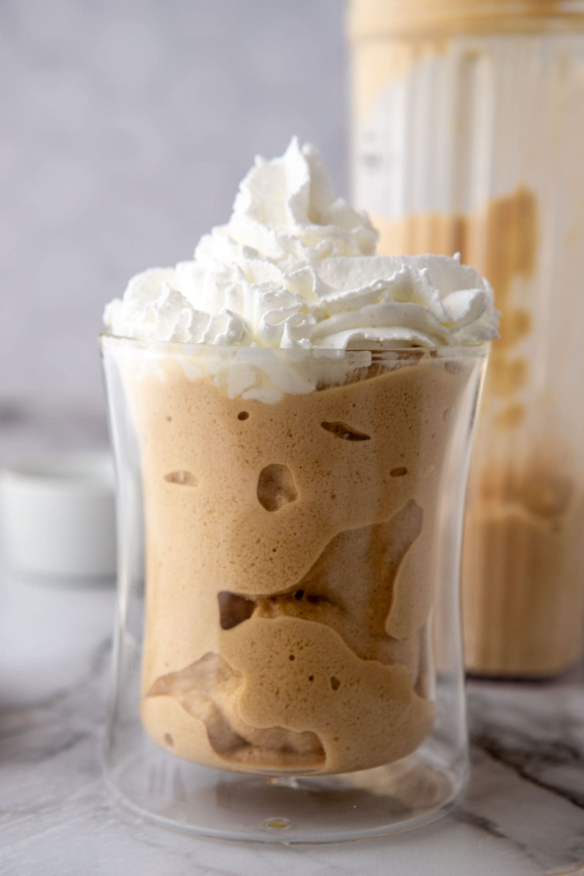 side shot of frozen mixture in a glass with whipped cream on top