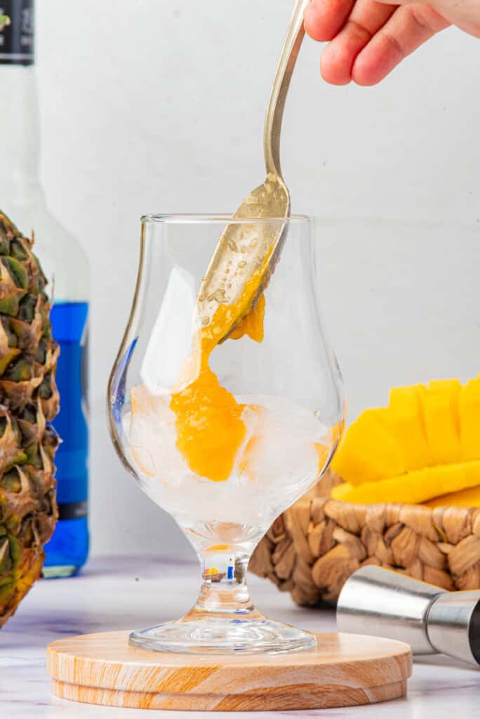 Mango puree being added to ice for Cheddar’s Island Tiki Cocktail