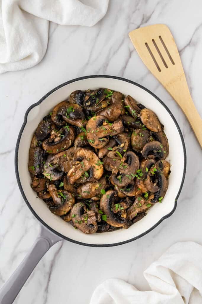 vegetables in white skillet with wooden spatula