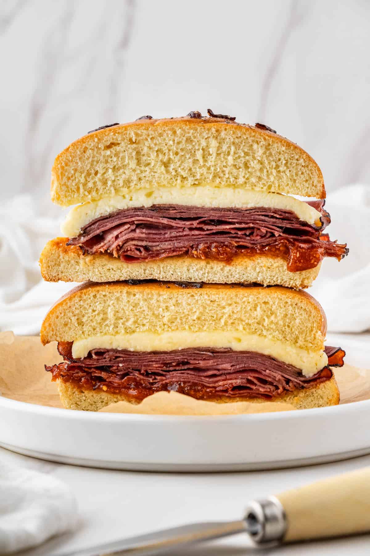 Arby's Beef and Cheddar copycat recipe on a white plate cut in half and stack onto of each other