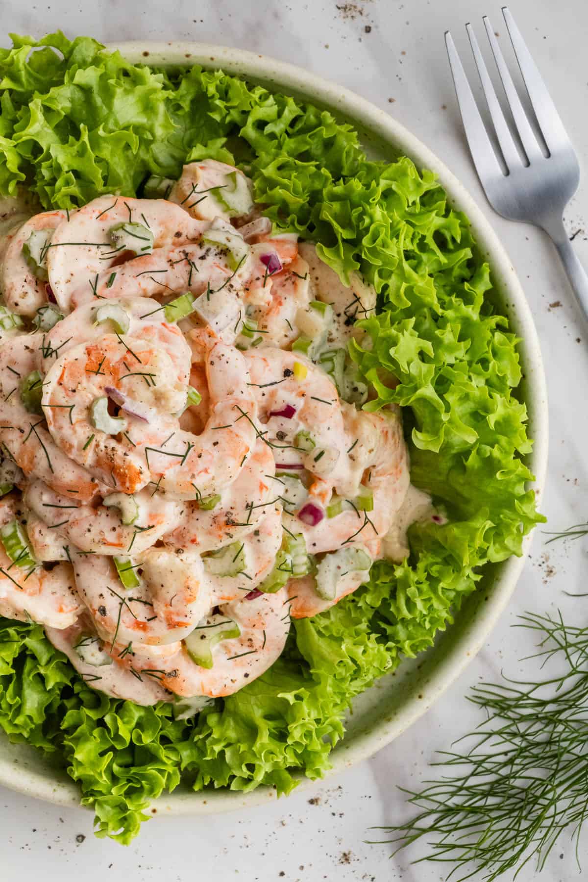 overhead view of Old Bay Shrimp Salad on a bed of greens in white bowl