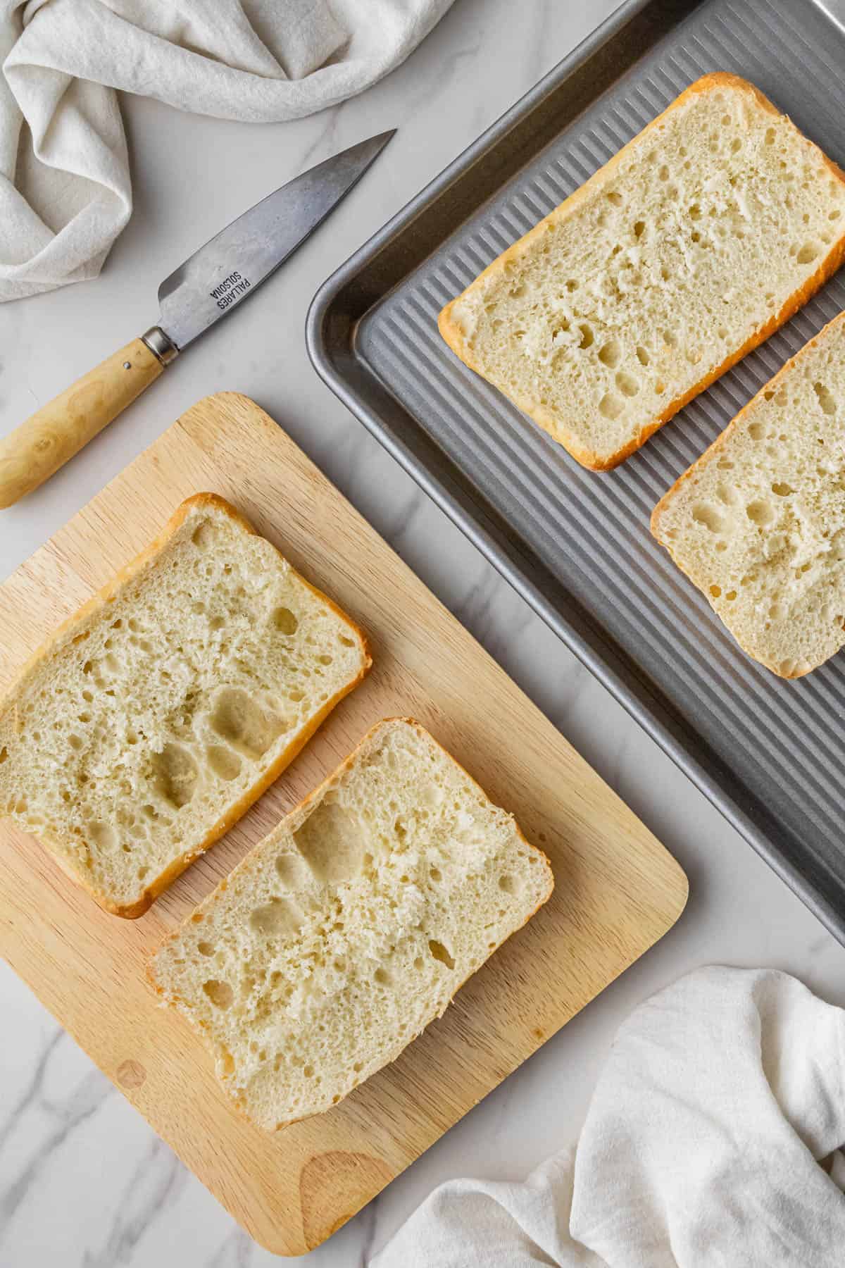 pieces of ciabatta bread on baking sheet and wooden cutting board