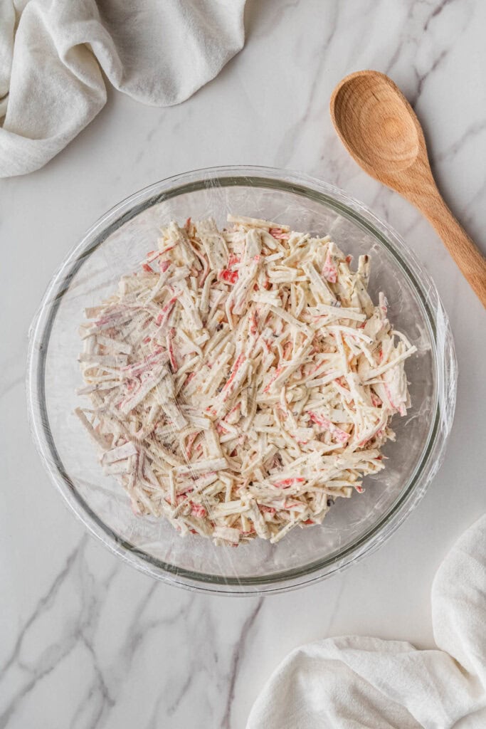 ingredients mixed in clear bowl with wooden spoon after chilling