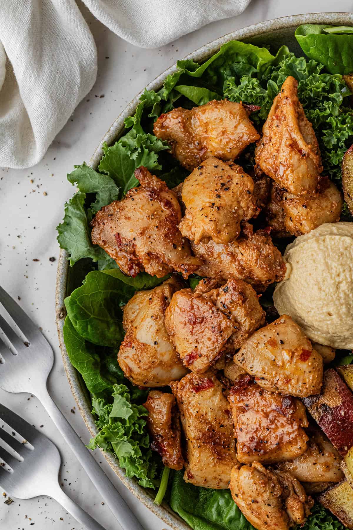 close up of Cava Honey Harissa Chicken recipe with dollop of hummus