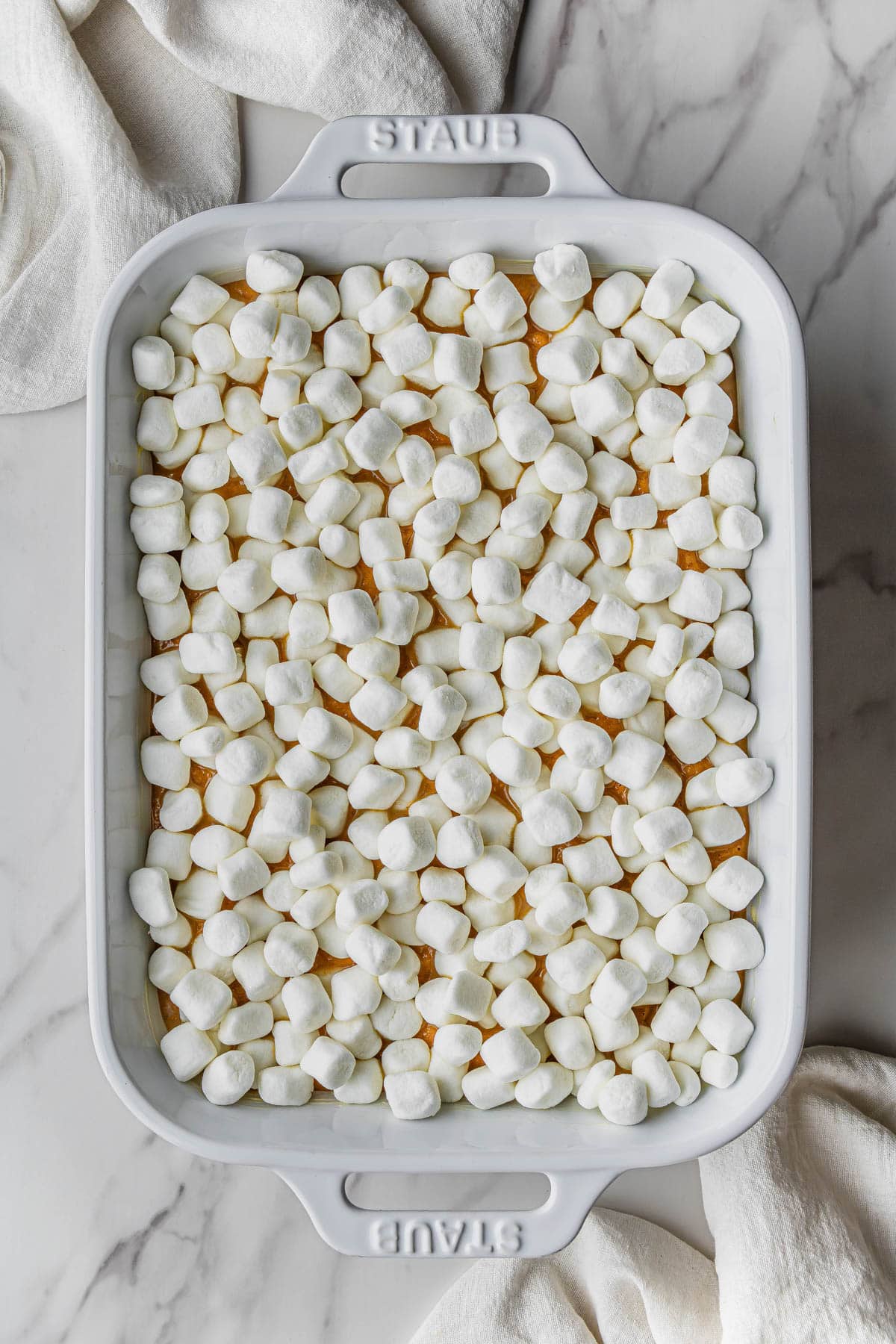 marshmallows on top of base mixture in white casserole dish