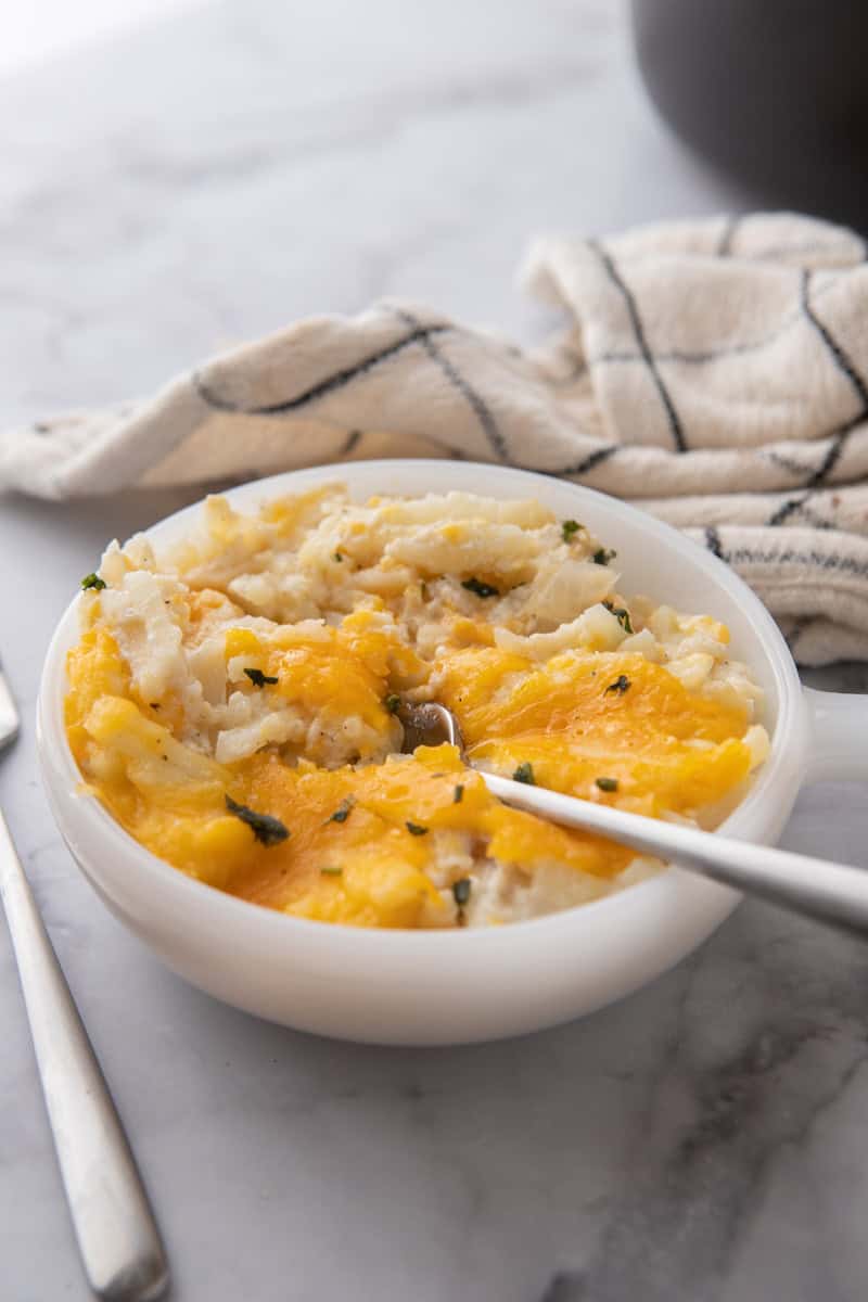 Cracker Barrel Cheesy Hash Brown Recipe crock pot in a bowl with a fork