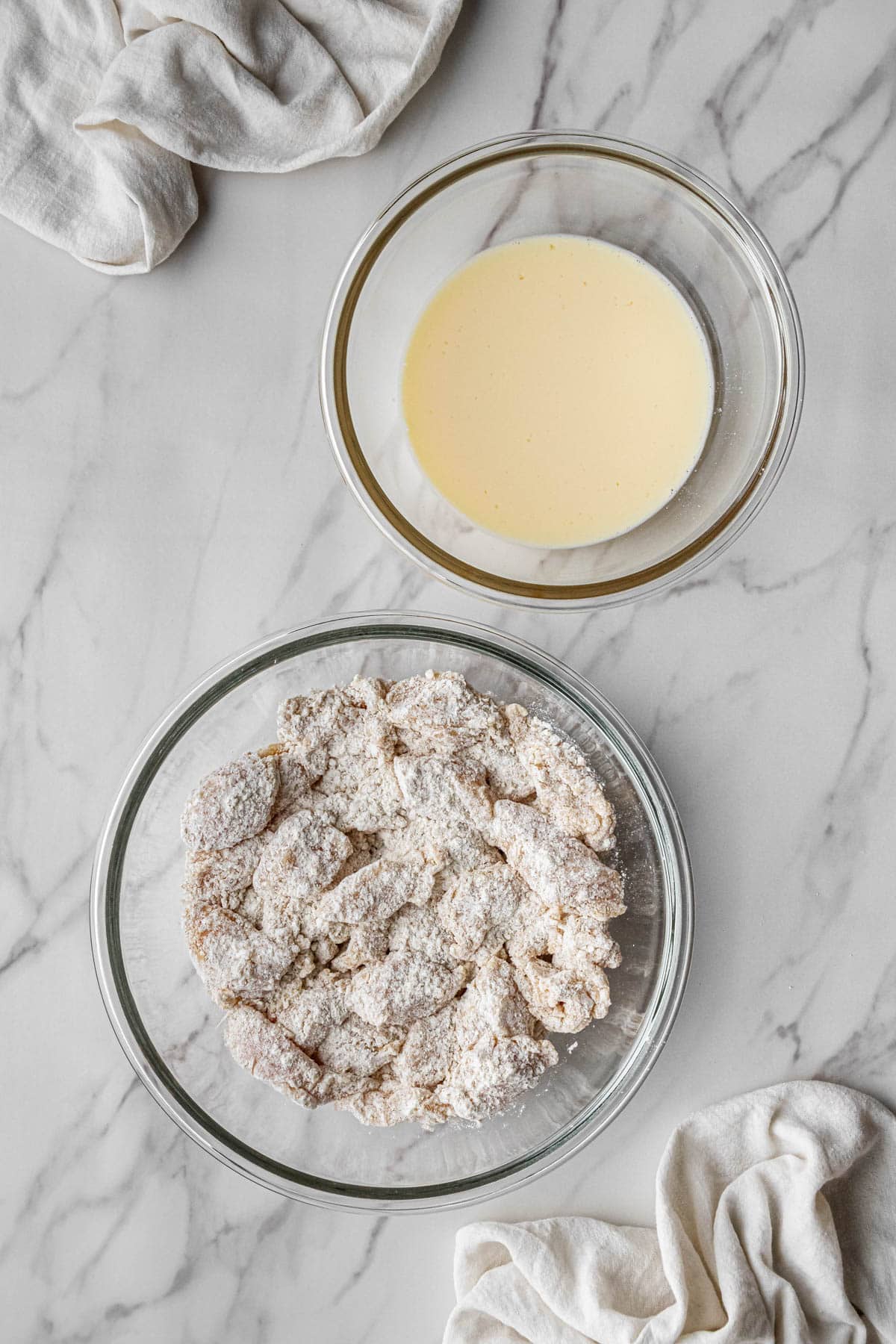 meat pieces in breading mixture bowl with wet mix beside in another bowl