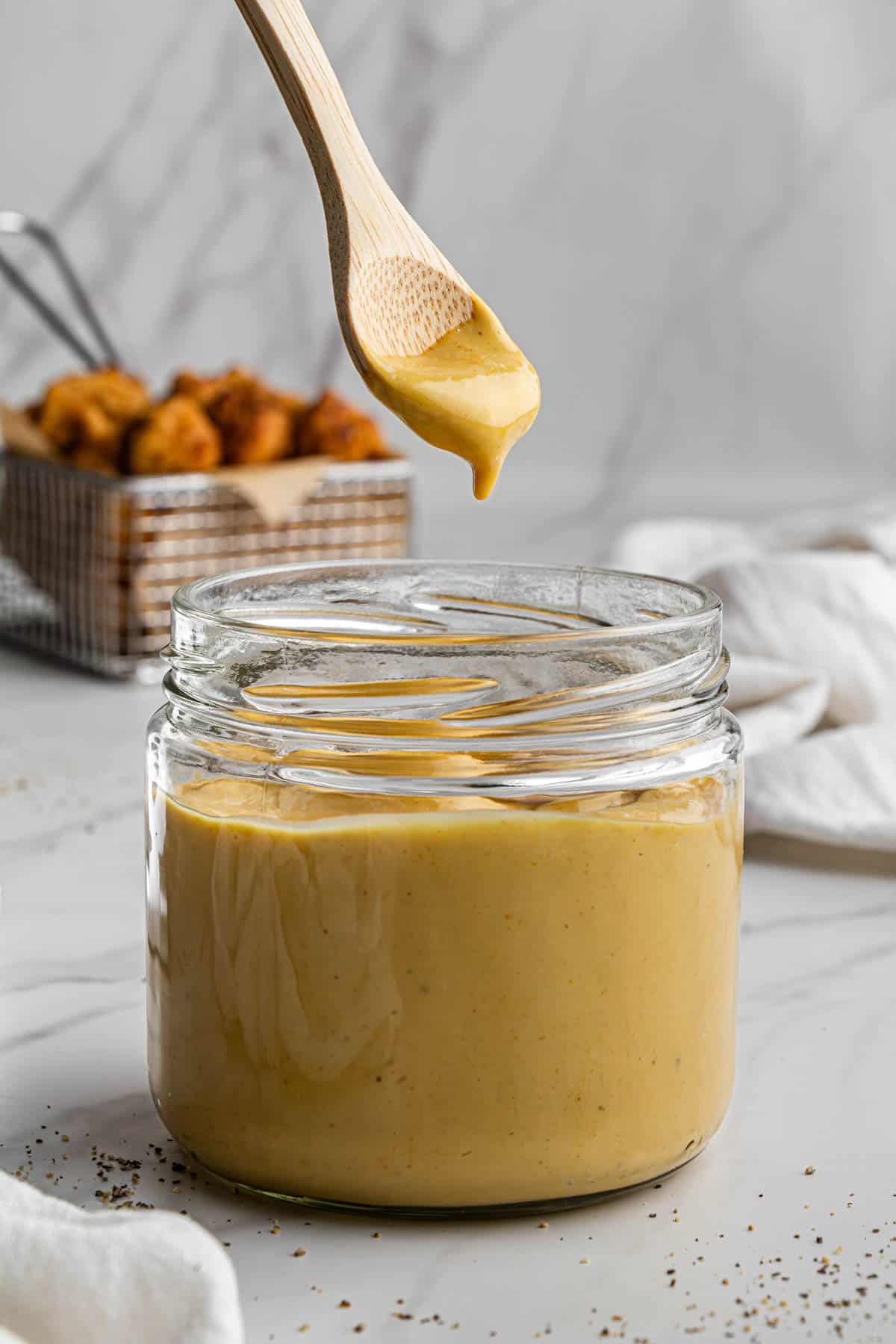 chick-fil-a sauce copycat recipe in a clear jar with wooden spoon over it