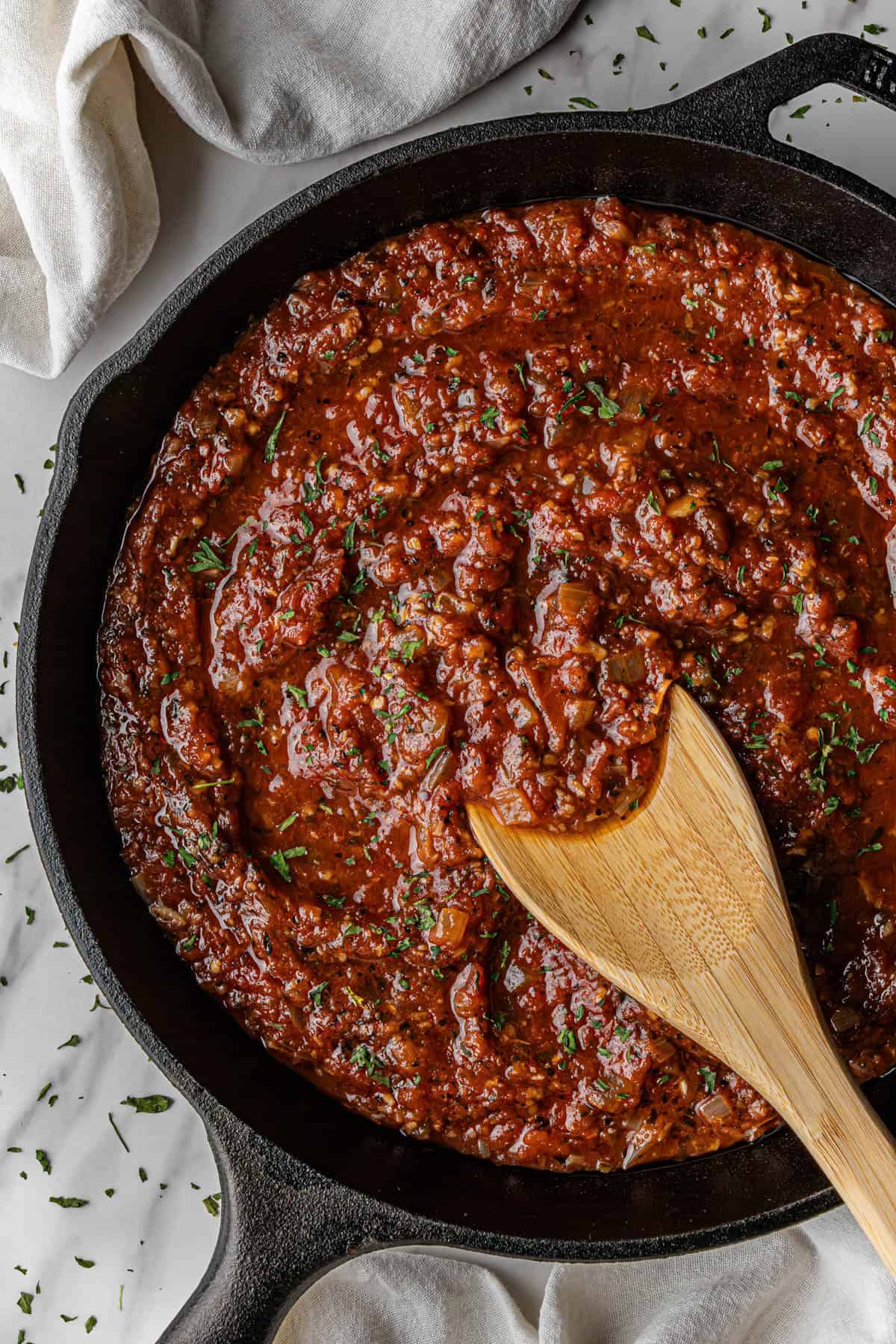 overhead view of Olive Garden marinara sauce with wooden spoon in cast iron skillet