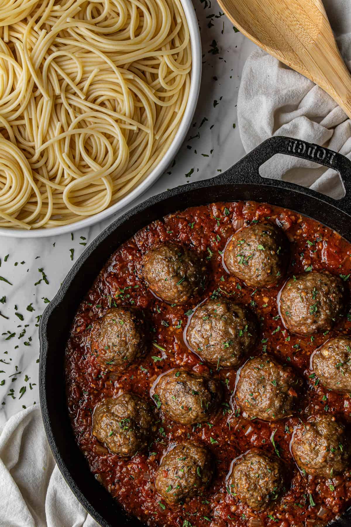a fork in the olive garden spaghetti and meatballs recipe on a plate and skillet