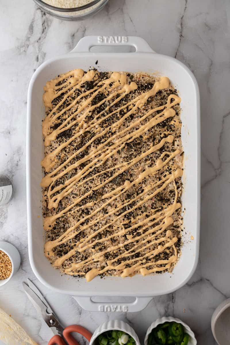 rice and seafood layered in a baking dish with toppings