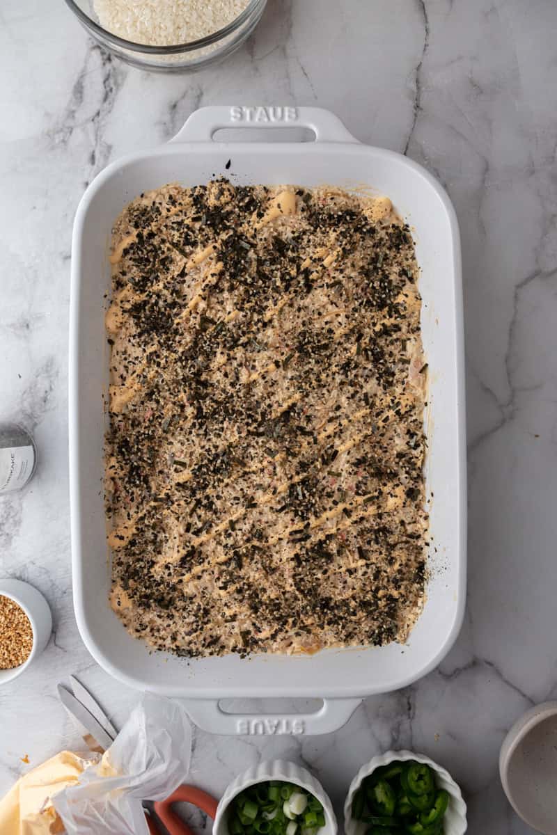 rice and seafood layered in a baking dish with toppings