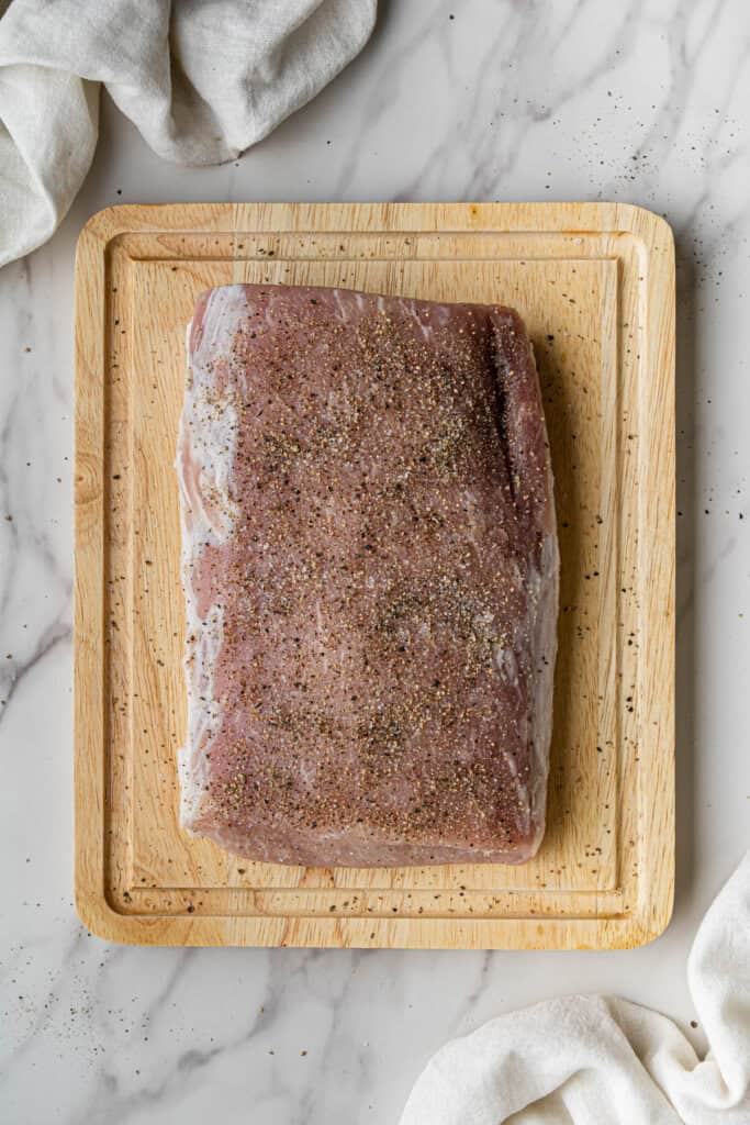 Flat lay shot of a big piece of seasoned meat on a wooden board.